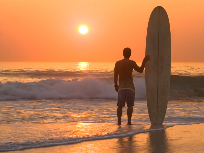 Man with surf board at sunrise